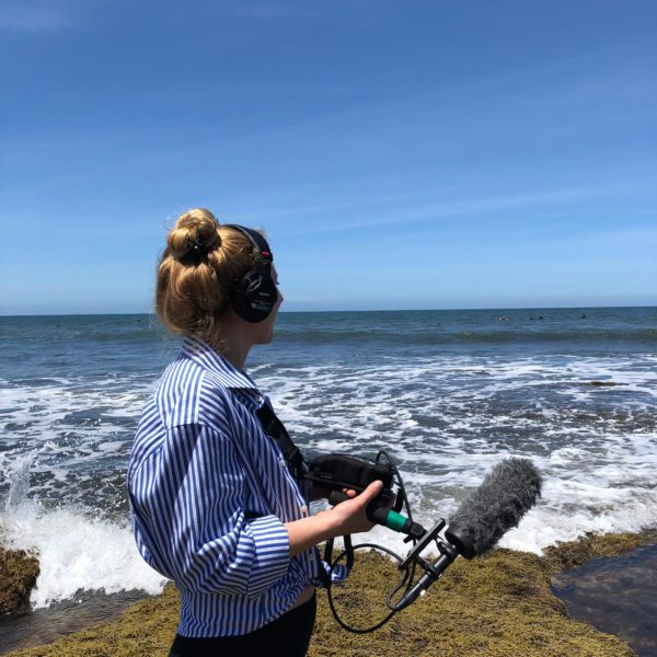 Michelle Macklem at beach holding a microphone